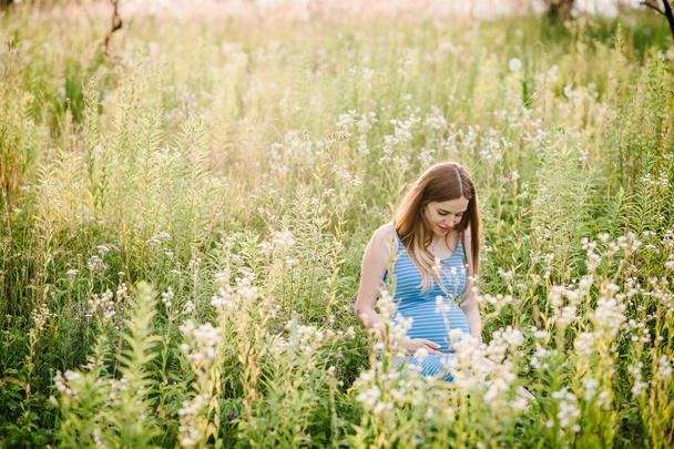 junge schwangere glückliche Frau spaziert im grünen Sommerpark - Foto, Bild