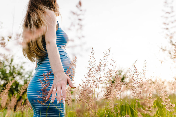 Terhes fiatal nő élvezi nyári nap, zöld mezőben   - Fotó, kép