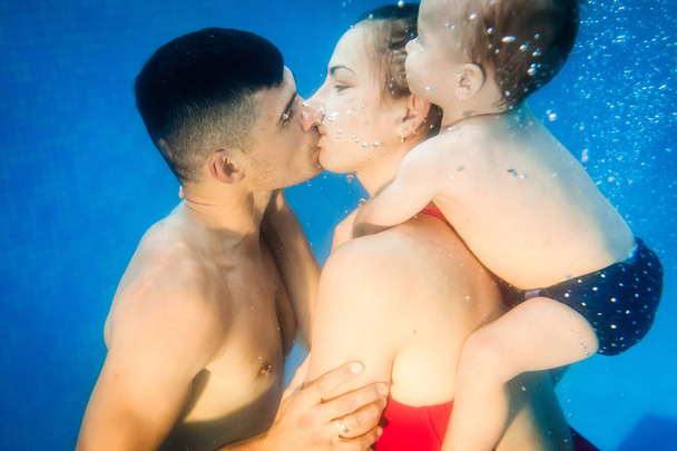 Young mother and father teaching son to swim on swimming lesson underwater with pool - Foto, Imagem