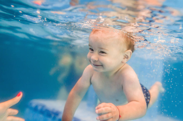 Μικρό αγόρι που κολυμπάει κάτω από το νερό στην παιδική πισίνα - Φωτογραφία, εικόνα