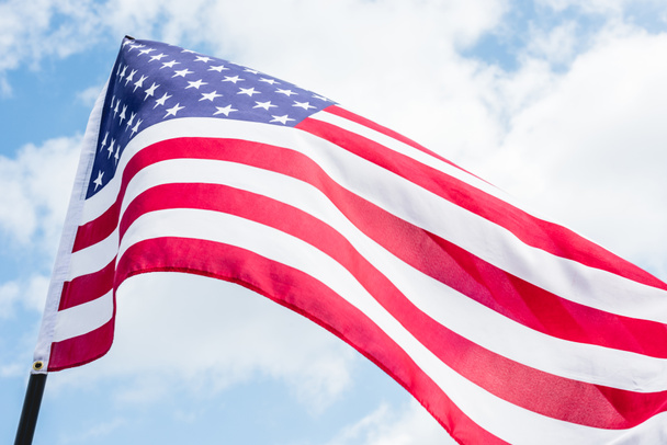 low angle view of american flag with stars and stripes against blue sky - 写真・画像
