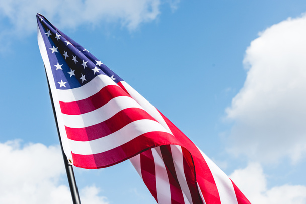 lage hoekmening van sterren en strepen op Amerikaanse vlag tegen blauwe hemel met wolken - Foto, afbeelding
