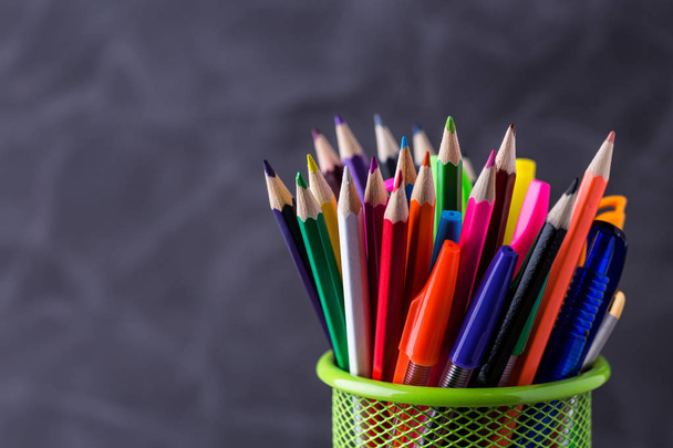Pens and pencils in metal holder in front of wall background  - Фото, зображення