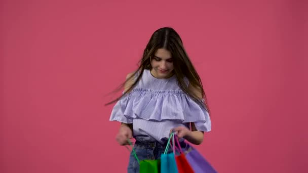 Girl gets a shoe from the bag and is happy. Pink background - Video