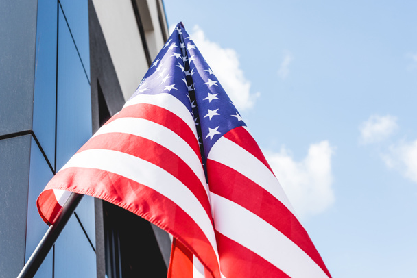 Widok niskiego kąta flagi narodowej Ameryki z gwiazdami i paskami w pobliżu budynku  - Zdjęcie, obraz