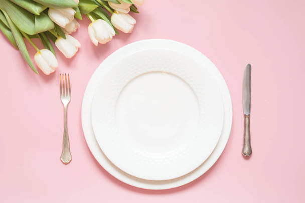 Elegant table setting with white tulip on pink table. Romantic spring dinner. - Foto, afbeelding