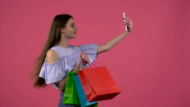 Girl make selfies with colorful packages. Pink background - Footage, Video