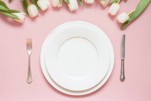 ピンクのテーブルの白いチューリップが付いている優雅なテーブルの設定。ロマンティックな春のディナー. - 写真・画像