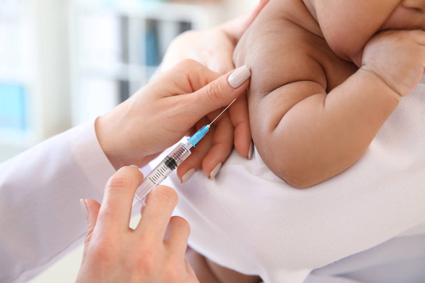 小さな赤ちゃんの診療所で注射を与える小児科医 - 写真・画像