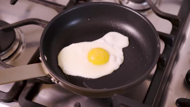 Žena v domácí kuchyni smažení smažené vejce v pánvi na snídani na plynový sporák - Záběry, video