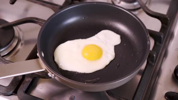 Žena v domácí kuchyni smažení smažené vejce v pánvi na snídani na plynový sporák - Záběry, video