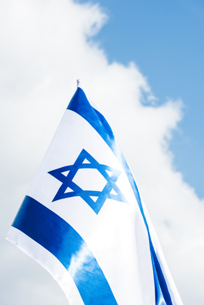 low angle view of national israel flag with blue star of david against sky with clouds  - 写真・画像