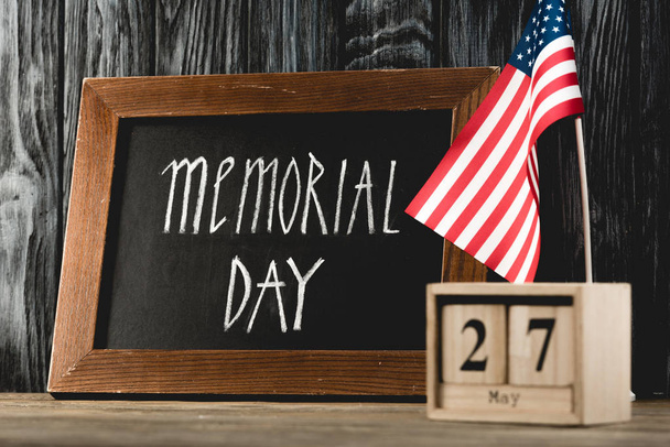 schoolbord met Memorial Day belettering in de buurt van houten kubussen met datum en Amerikaanse vlag  - Foto, afbeelding
