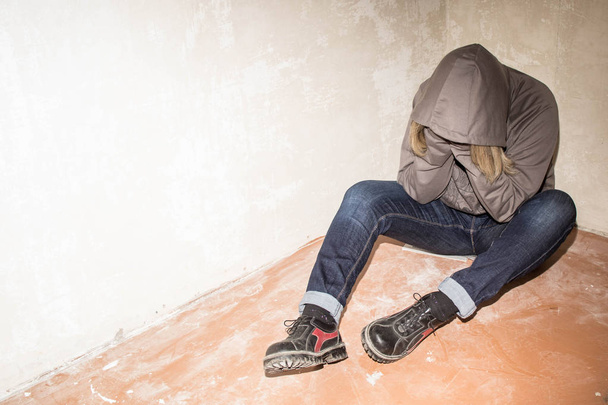 Retrato del hombre triste, drogadicto sentado en el suelo en la esquina
 - Foto, Imagen