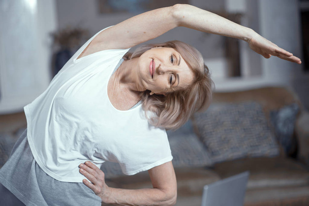 Middle aged woman doing yoga at home - Foto, afbeelding