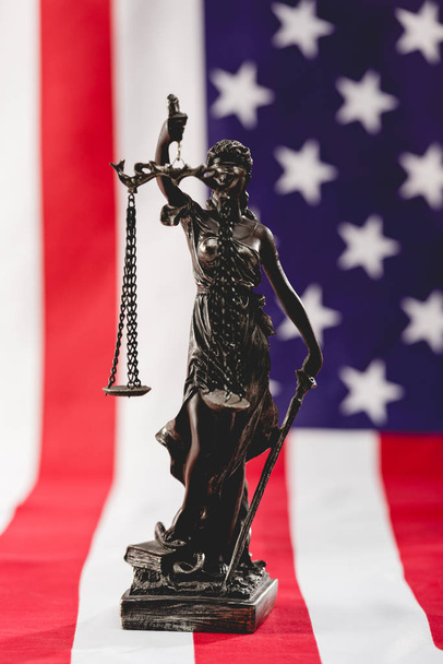 Selektiver Fokus der Justiz Statue nahe der amerikanischen Flagge mit Sternen und Streifen - Foto, Bild