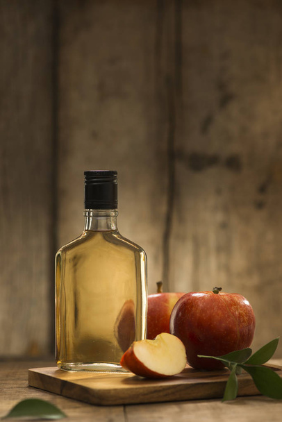 Bottle of fresh cider near autumn apples on dark wooden background  - Photo, Image