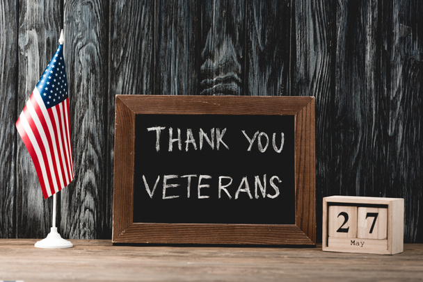 tablero negro con letras de los veteranos de gracias cerca de bandera americana y cubos con fecha
 - Foto, Imagen