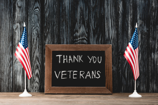 tablero negro con letras de los veteranos de gracias cerca de banderas de América
 - Foto, imagen