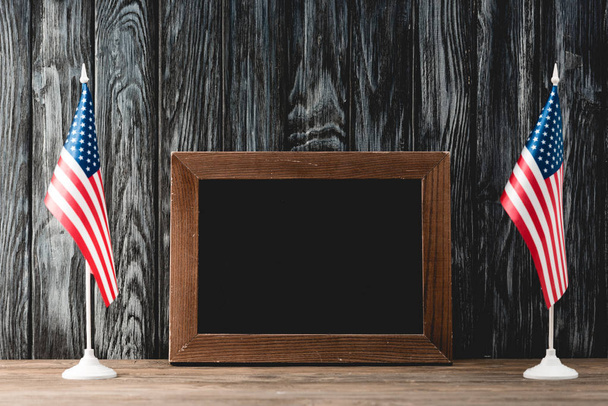  empty black board near american flags with stars and stripes - Foto, imagen