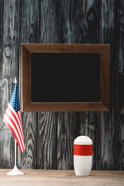 empty chalkboard near funeral urn with ashes and american flag - 写真・画像
