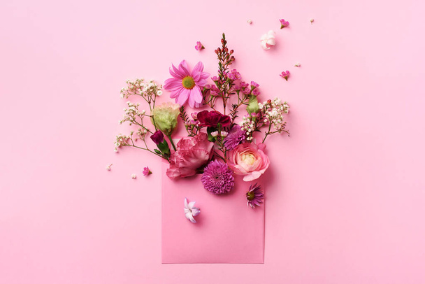 Pink envelope with spring flowers. Floral composition, creative layout. Flat lay, top view. Spring, summer or garden concept. Present for Woman day - Foto, afbeelding