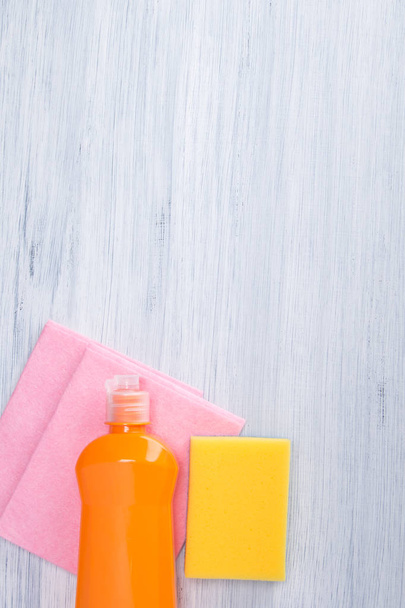 on a light background, a bottle of cleaning agent, a cleaning sponge and a pink rag, there is a place for the inscription - Фото, изображение