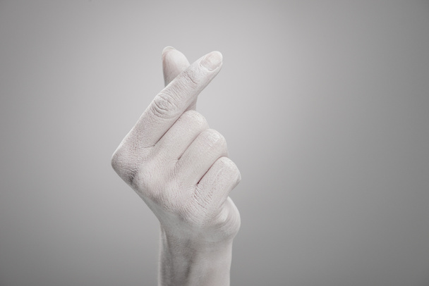 vista recortada de la mano femenina pintada de blanco que muestra el signo en forma de corazón en gris
  - Foto, Imagen