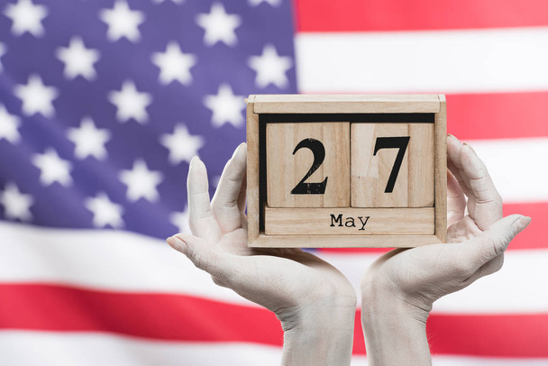 cropped view of female hands painted in white holding cubes with date near american flag  - Foto, Imagen