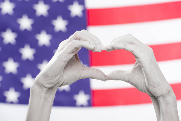 przycięte widok kobiece ręce malowane na biało pokazano w kształcie słyszalny znak w pobliżu amerykańskiej flagi - Zdjęcie, obraz