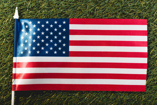 close up of american flag with stars and stripes on green grass - Foto, afbeelding