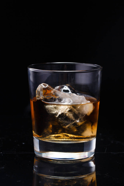 ein Glas mit Whiskey und Eis auf einem Hintergrund - Foto, Bild