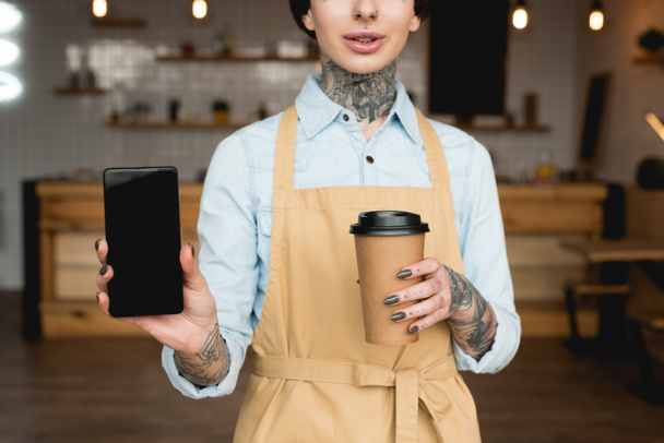 partial view of waitress holding paper cup and smartphone with blank screen - Photo, Image