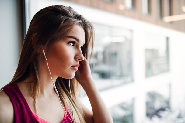A portrait of young girl or woman with earphones in a gym. Copy space. - Foto, Imagem