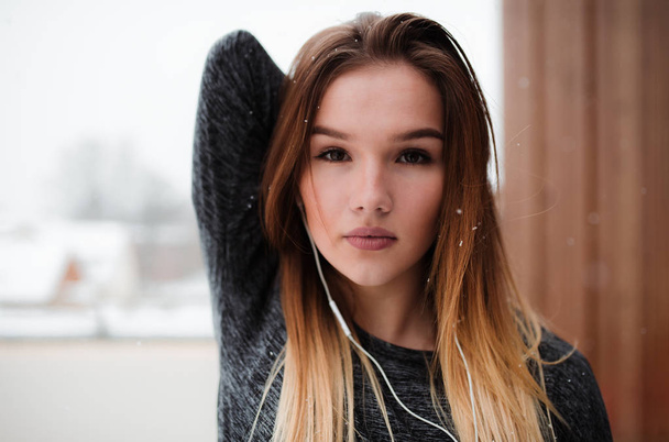 A portrait of young girl or woman with earphones doing stretching outdoors. - Foto, Bild