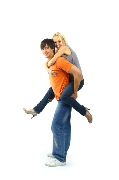 Happy young female enjoying a piggyback ride on boyfriends back against whi - Foto, afbeelding