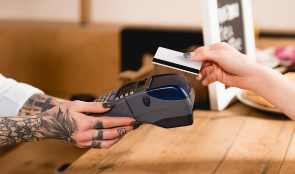 vue recadrée du client détenant une carte de crédit près du terminal de paiement dans le café
  - Photo, image