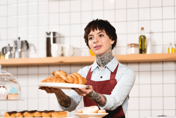 mosolygó barista edény, croissant-t, a kinyújtott kezet tartó - Fotó, kép