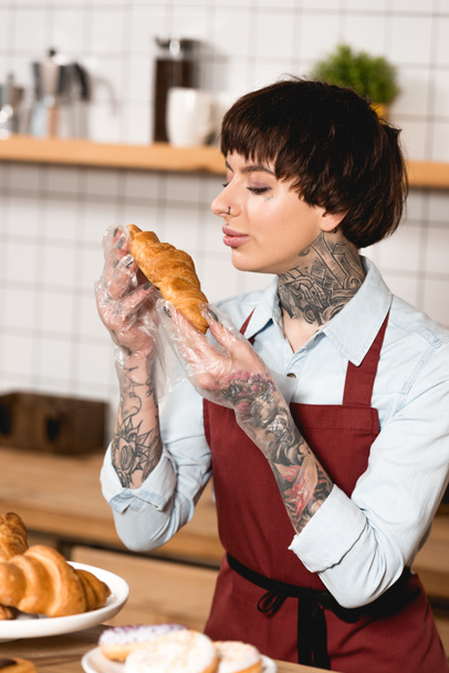 hübsche Barista in Einmalhandschuhen mit leckerem Croissant - Foto, Bild