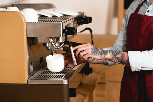 partial view of tattooed barista preparing coffee on coffee machine  - Foto, Bild