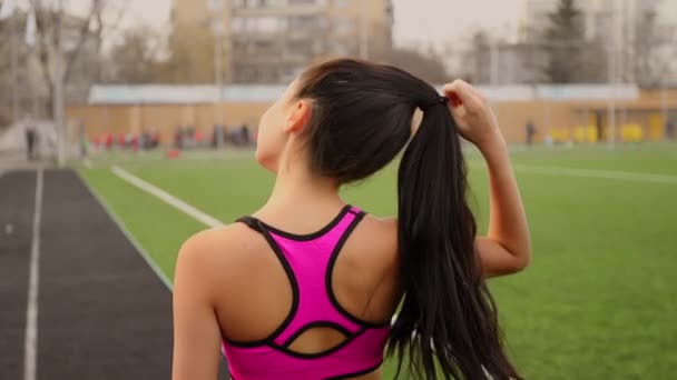 Fiatal sportos ázsiai lány sétál a stadionban, edzés után, és lehetővé teszi, hogy a haja. - Felvétel, videó