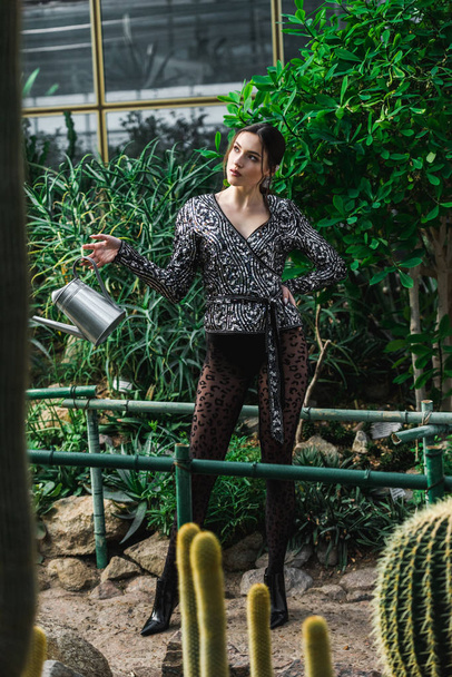 Sexy jonge vrouw in panty holding gieter in de Oranjerie - Foto, afbeelding
