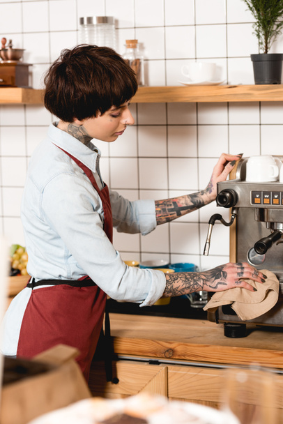 Selektiver Fokus der hübschen Barista-Reinigungs-Espressomaschine mit Lappen im Café - Foto, Bild