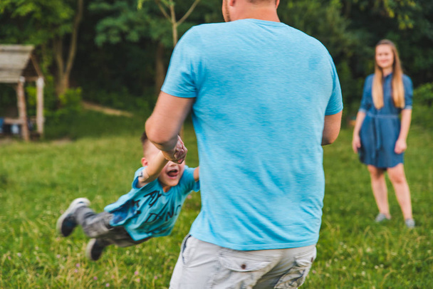 Mann spinnt Jungen auf der grünen Wiese. Herumspielen - Foto, Bild
