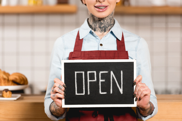 partial view of barista holding signboard with open inscription in coffee shop - Photo, Image