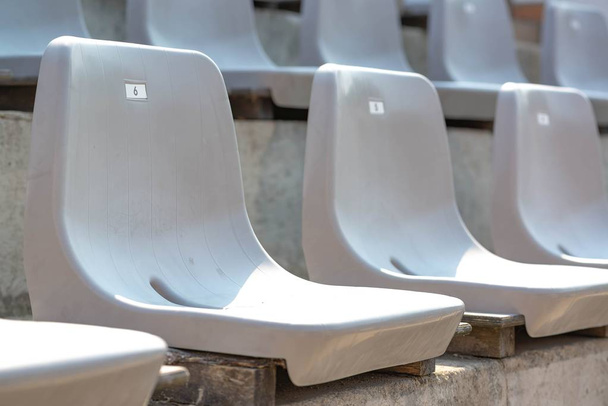 Leere weiße Tribünenreihen im Stadion mit Sonnenlicht - Foto, Bild