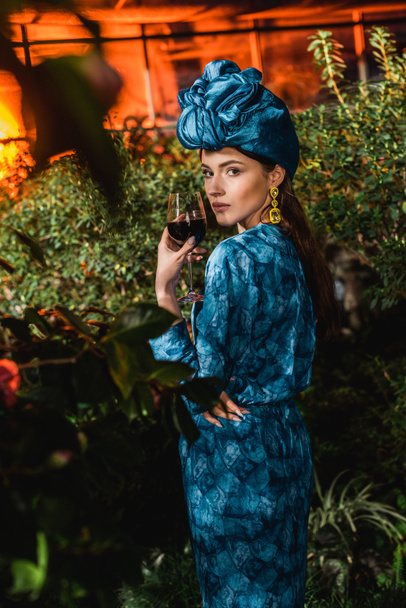 Belle femme en turban bleu tenant un verre de vin rouge en orangerie
 - Photo, image