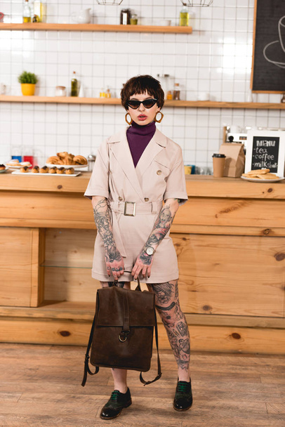 attrayant, femme d'affaires à la mode dans les lunettes de soleil debout au comptoir du bar à la cafétéria
 - Photo, image