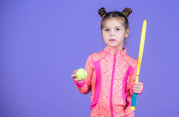 Childhood and active games. Sport upbringing. Small cutie likes tennis. Little baby sporty costume play tennis game. Teach me how to play tennis. Girl cute child double bun hairstyle tennis player - Foto, imagen