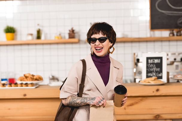 smiling, trendy businesswoman in sunglasses holding disposable cup - Photo, Image